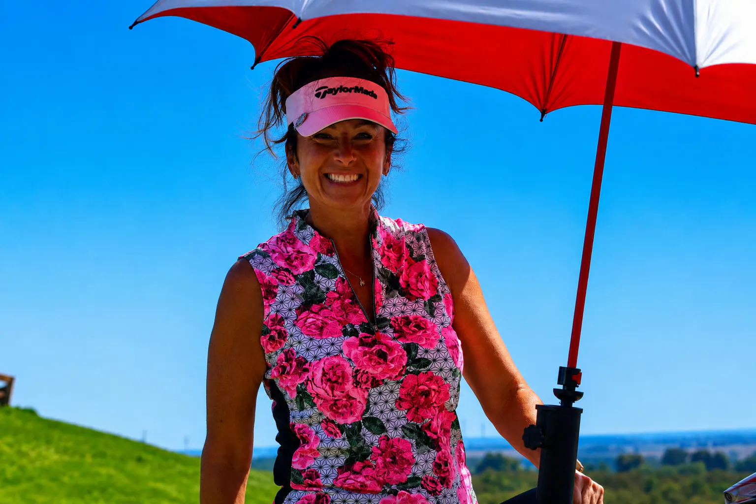 Golfeuse souriante sous un parasol rouge et blanc