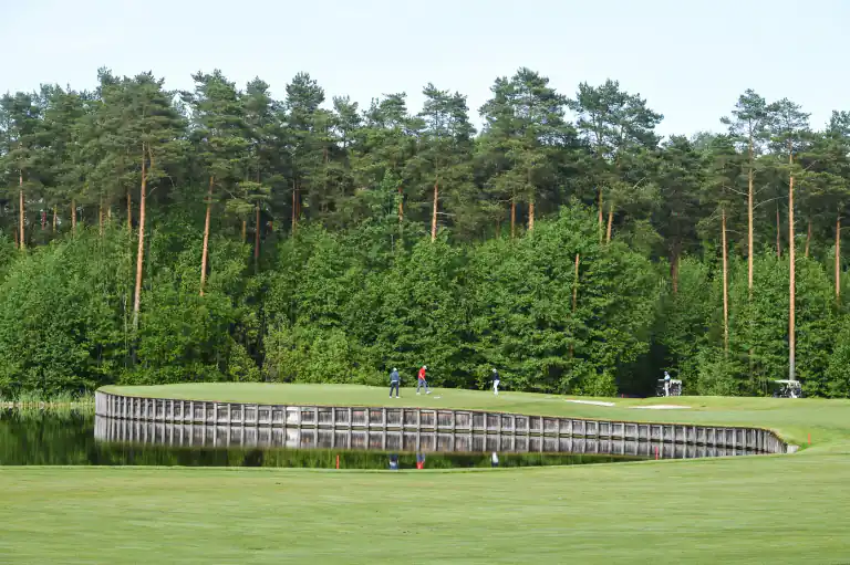 Golfers playing beside a woodland lake
